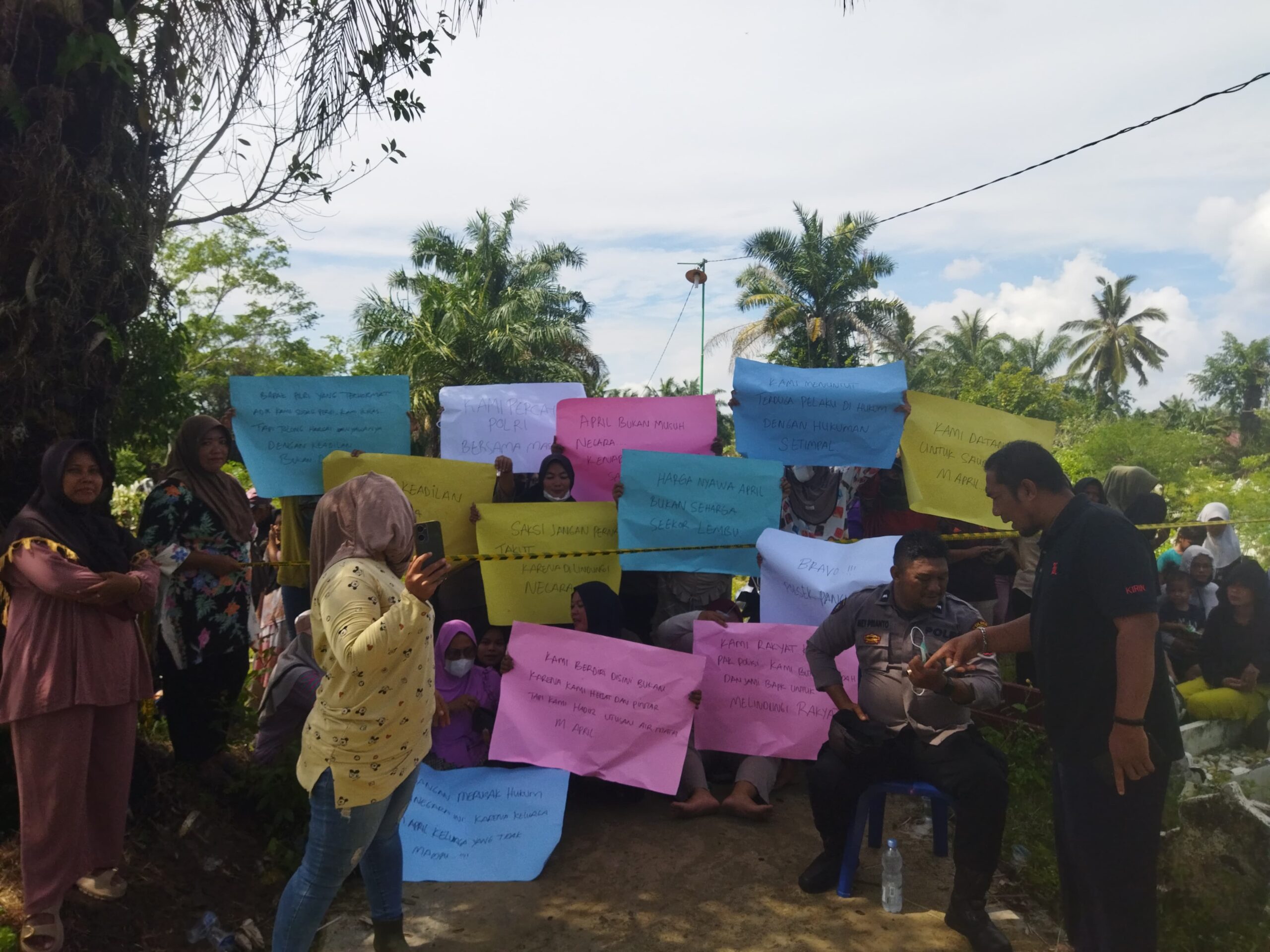 Ket foto : Warga Membawa Spanduk Kertas di Tempat Penggalian Makam, Agar Pelaku Pemukulan di Proses Hukum.